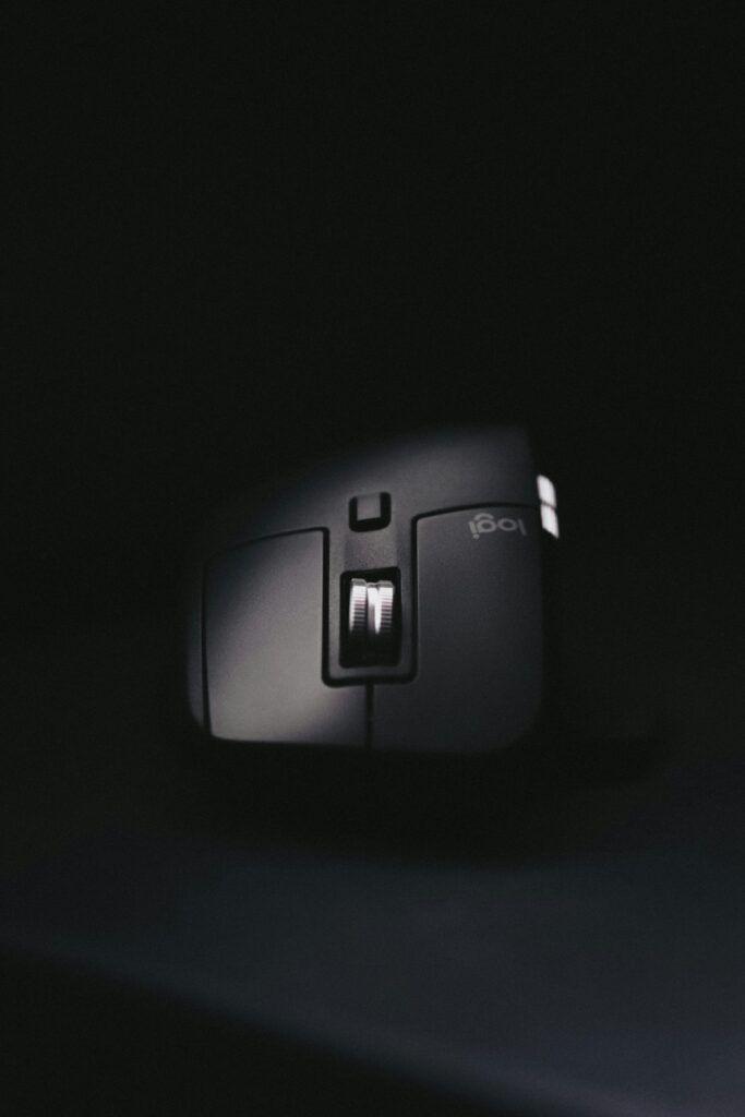 Close-up image of a black ergonomic computer mouse with a scroll wheel, isolated on a dark background.