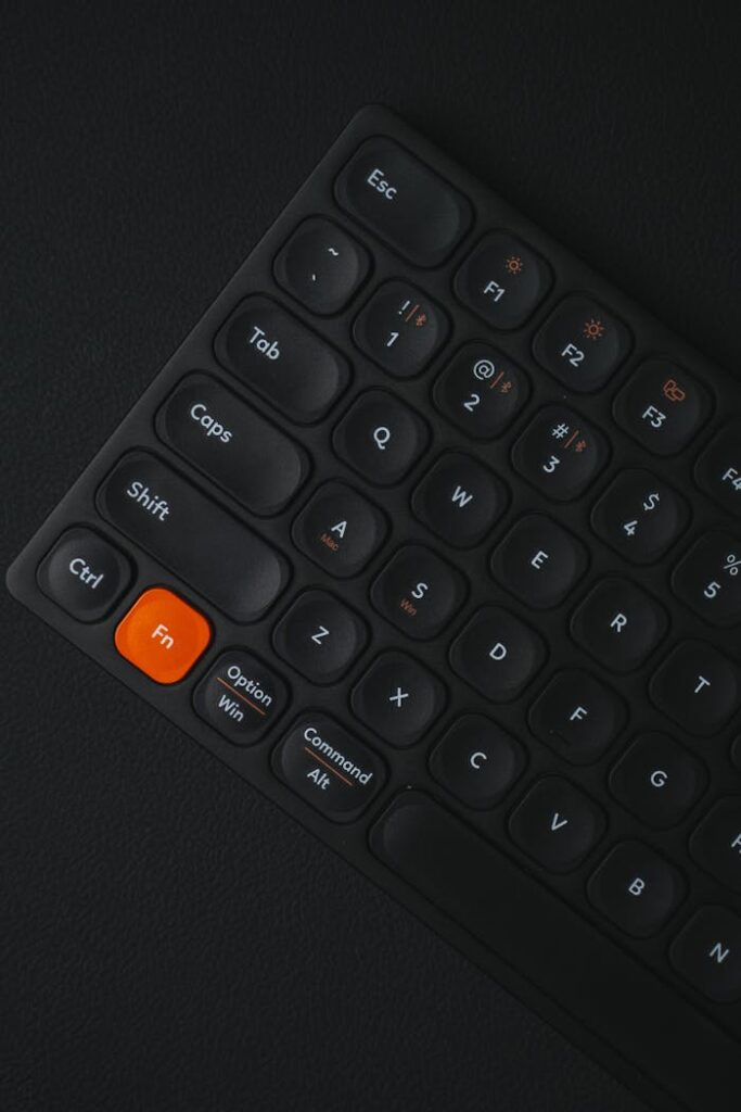 Close-up of a sleek black keyboard with an orange 'Fn' key, highlighting minimalistic design.
