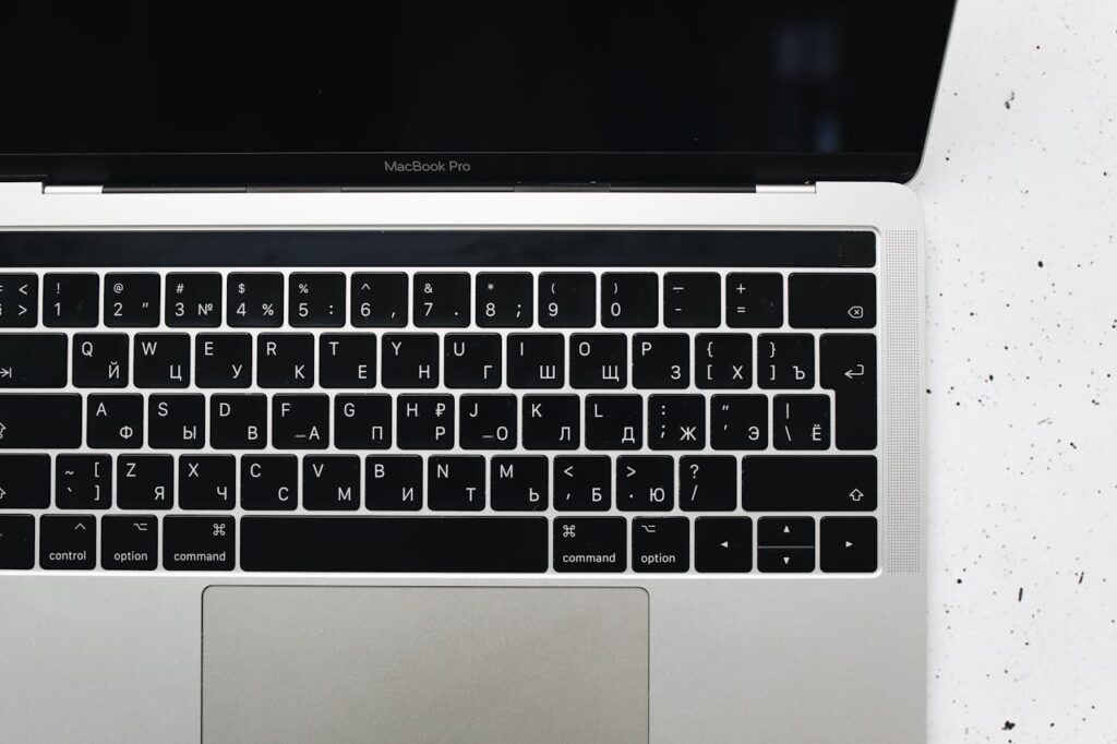 Top view of a MacBook Pro keyboard on a speckled marble surface, showcasing a Russian Cyrillic layout.